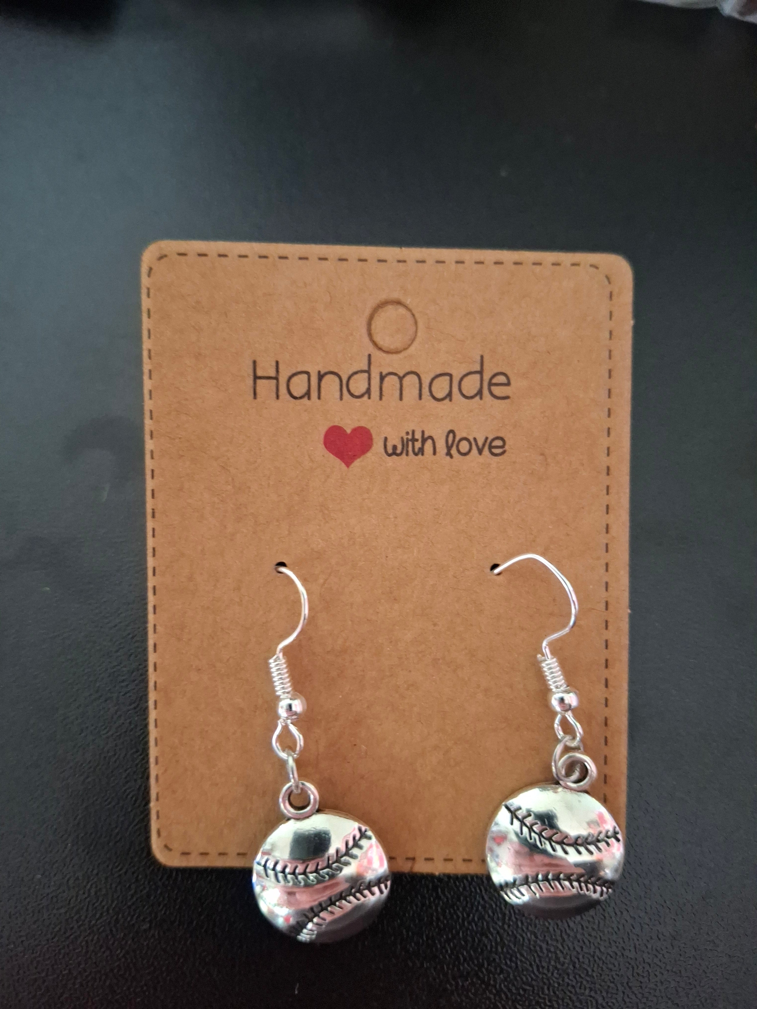 Pair of silver earrings on a 'Handmade with Love' card against a dark background