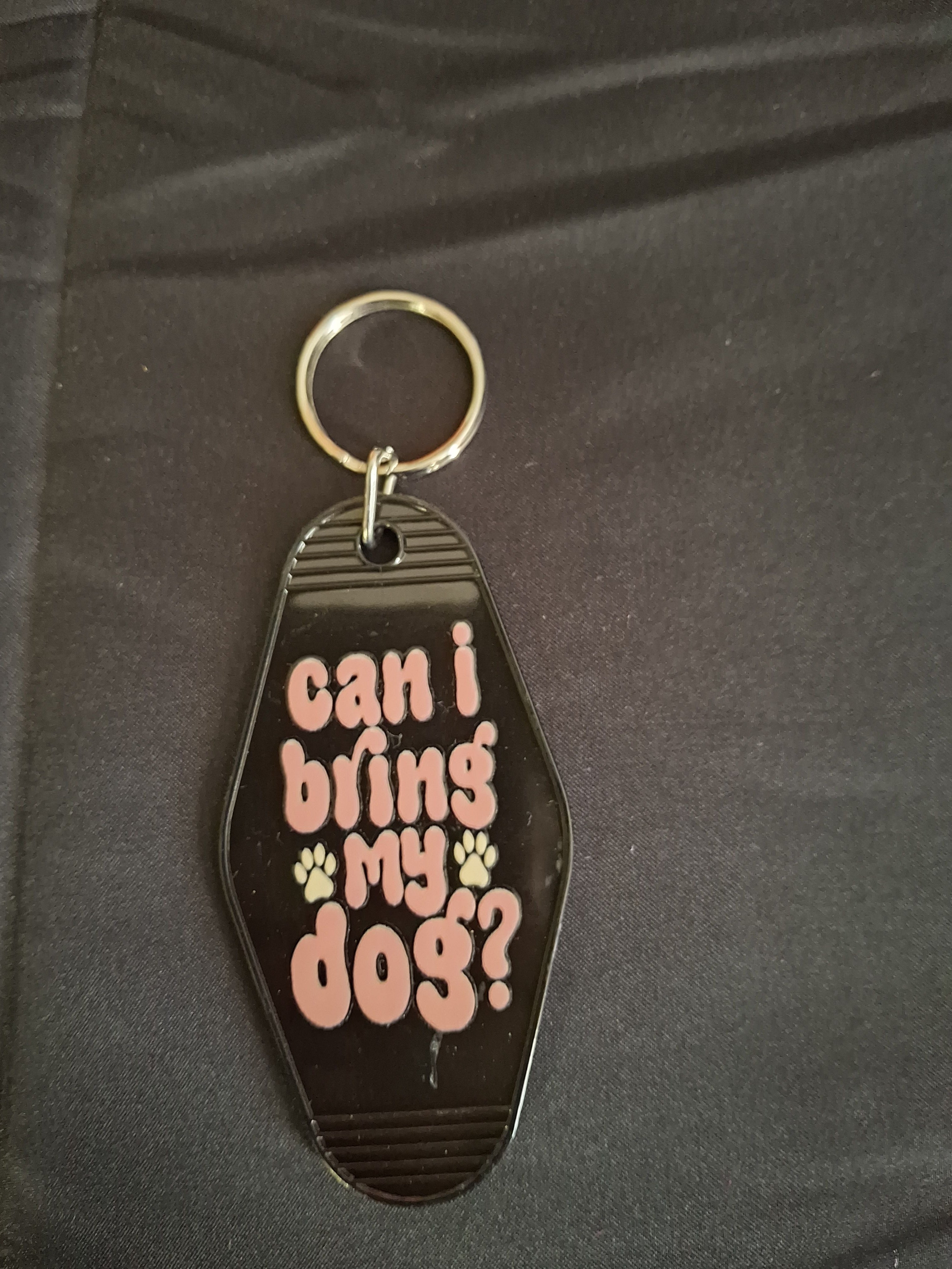 Keychain with text 'Can I bring my dog?' on a dark background