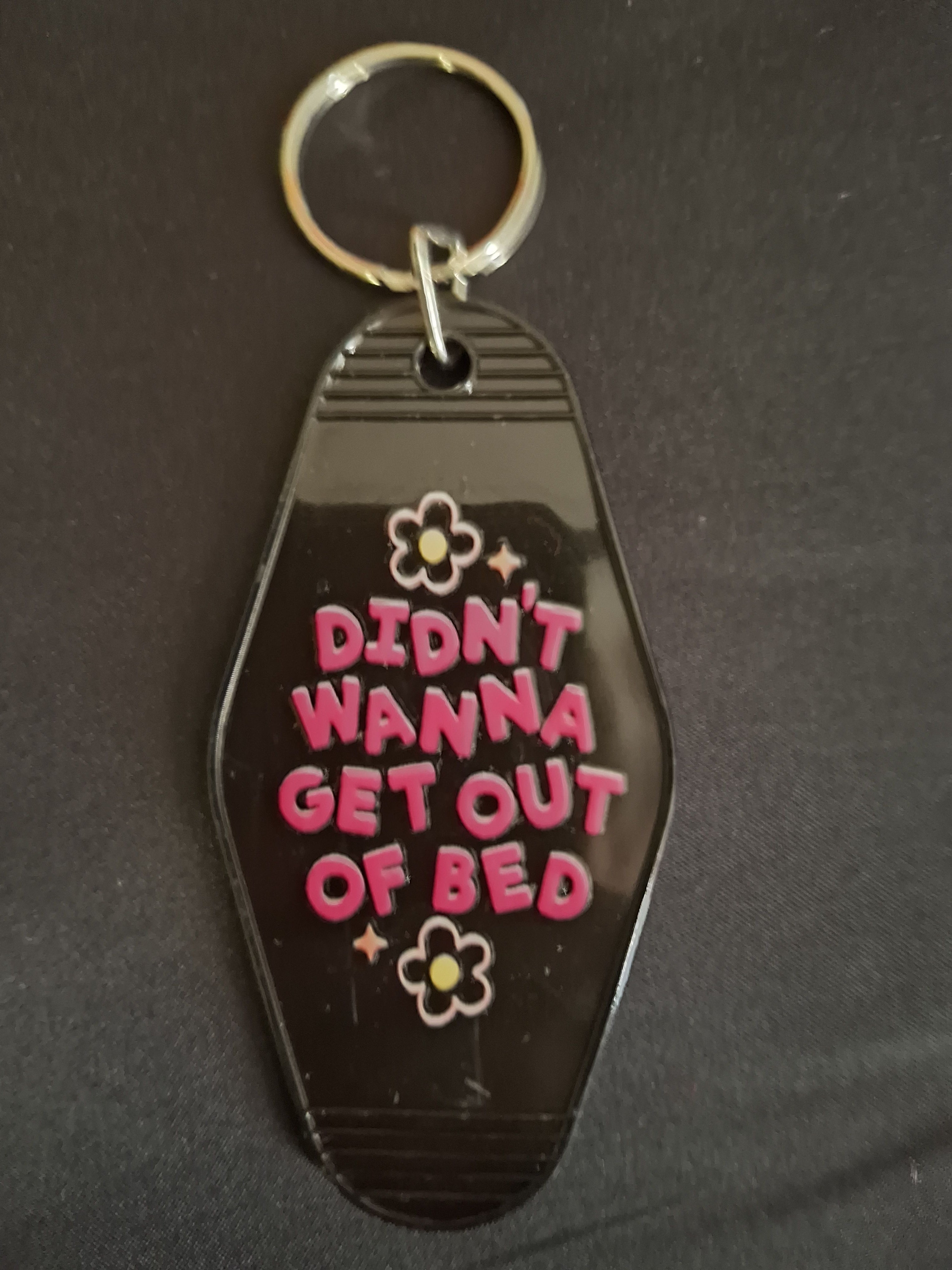 Keychain with text 'Didn't wanna get out of bed' on a dark background