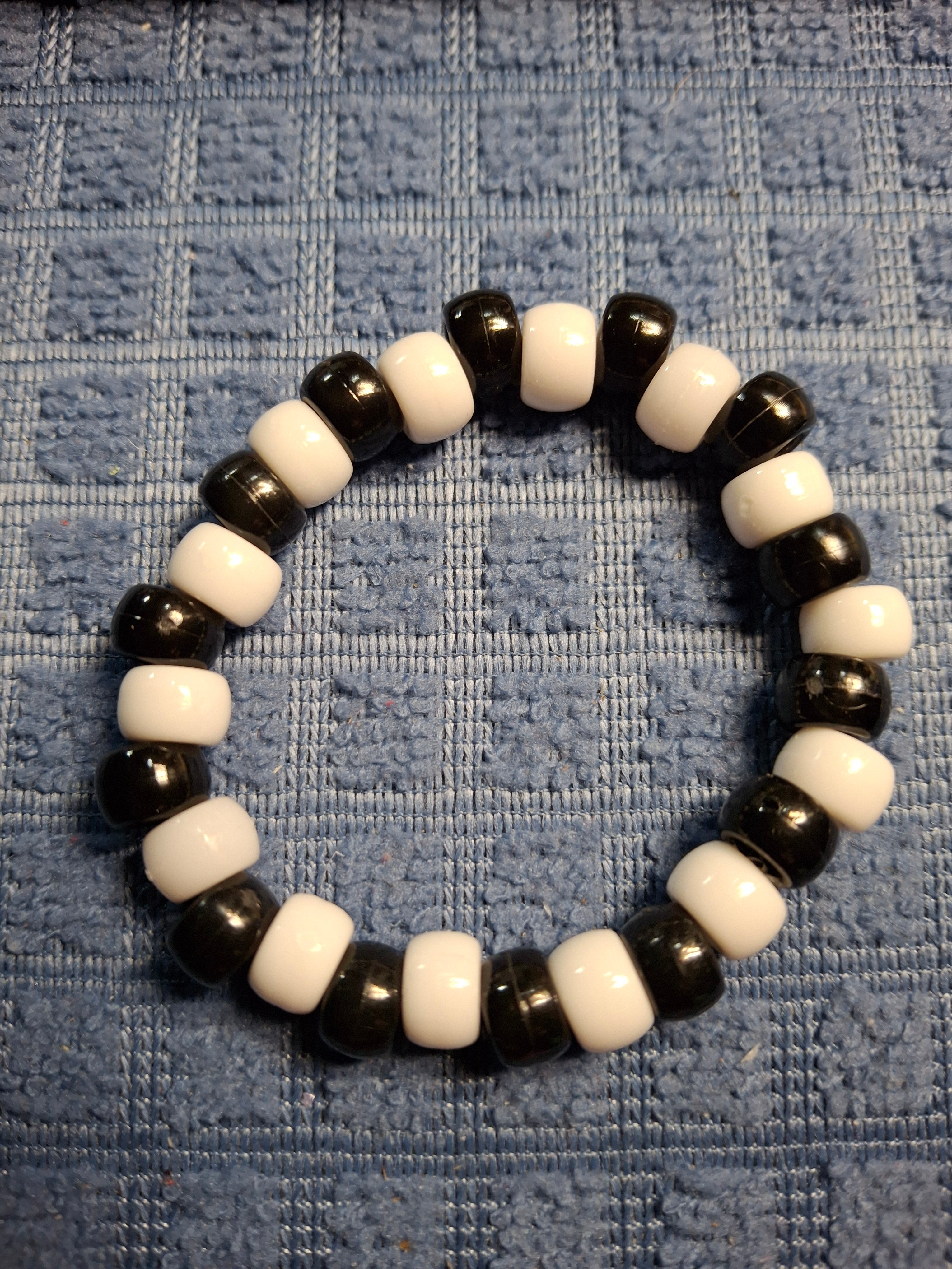 Black and white beaded bracelet on a textured blue fabric background