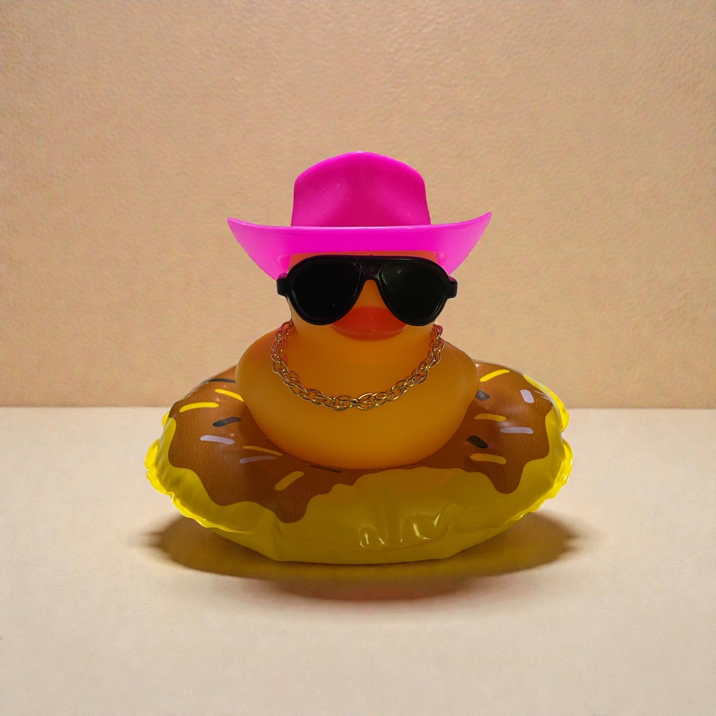 Yellow Duck with Pink Cowboy Hat, Black Sunglasses, Gold Necklace sitting on a Yellow Tube