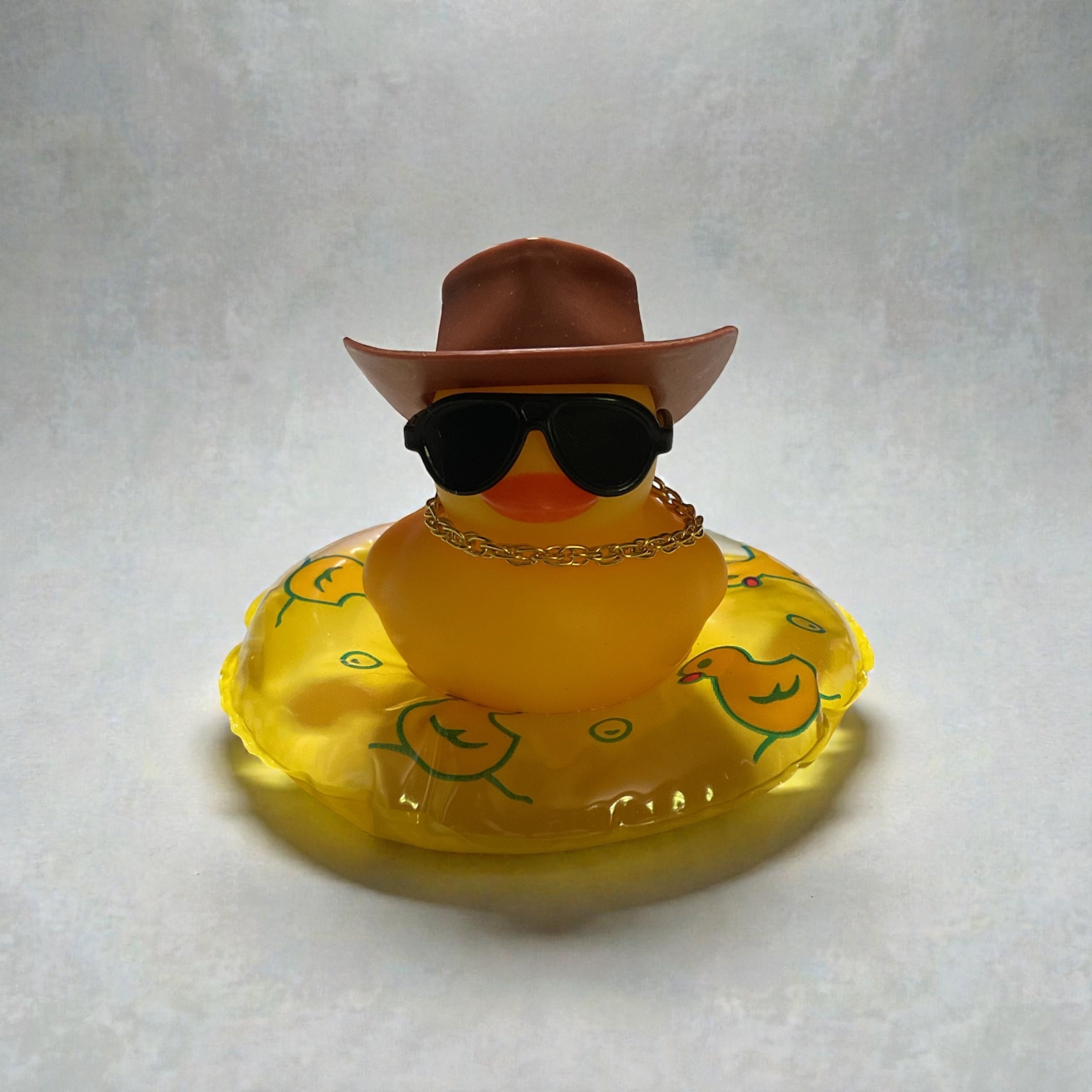 Yellow Duck with Brown Cowboy Hat, Black Sunglasses, Gold Necklace sitting on a Yellow Tube