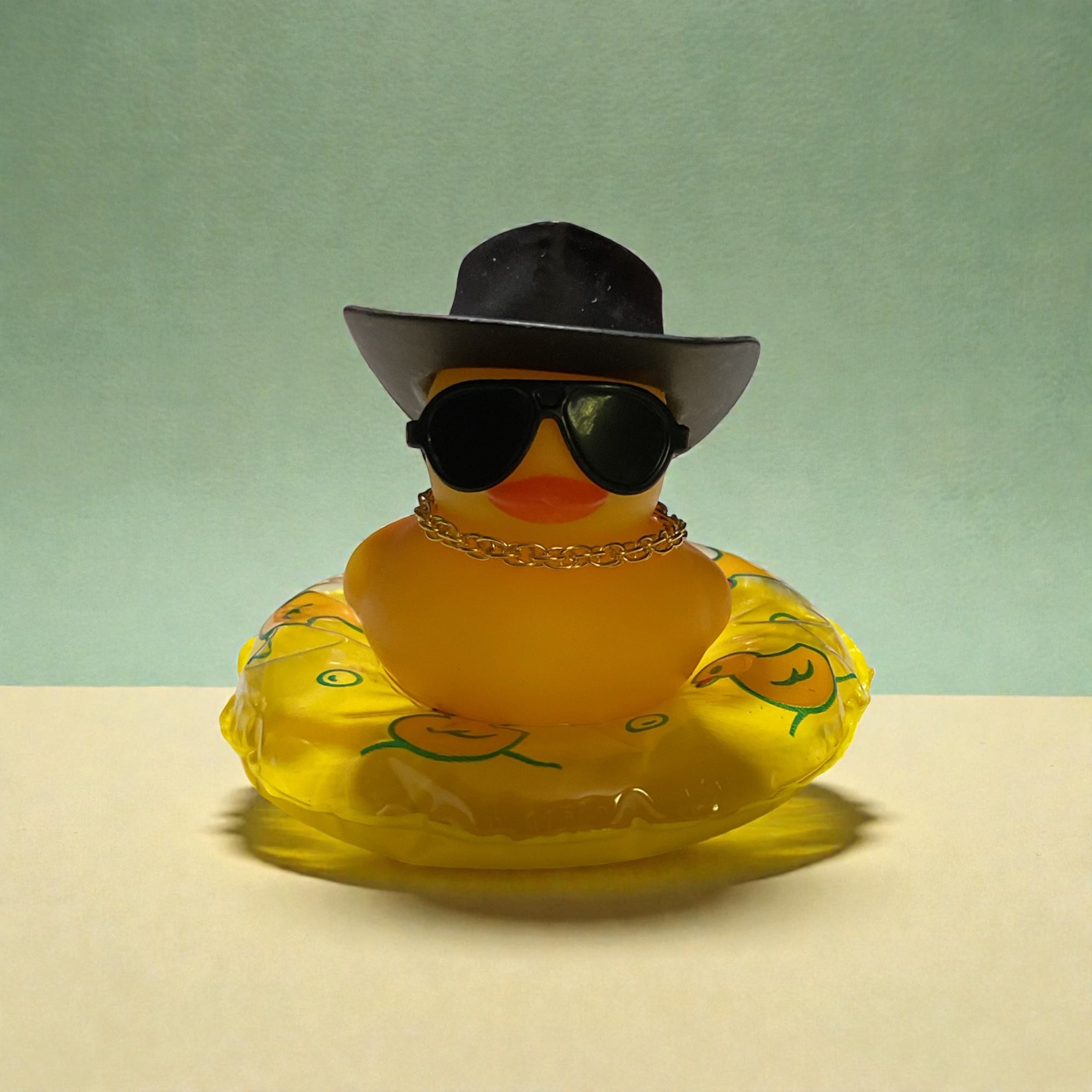 Yellow Duck with Black Cowboy Hat, Black Sunglasses, Gold Necklace sitting on a Yellow Tube