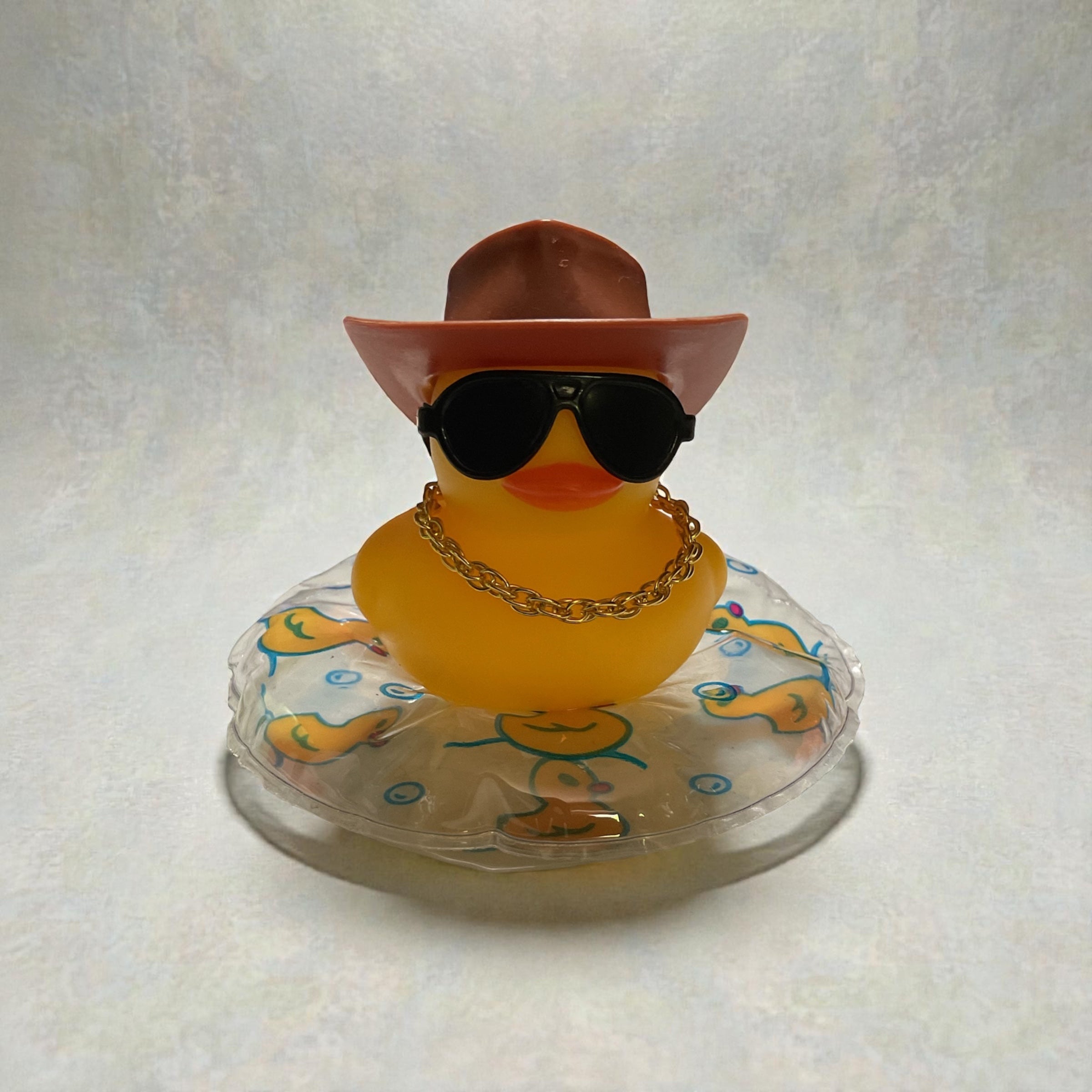 Yellow Duck with Brown Cowboy Hat, Black Sunglasses, Gold Necklace sitting on a Clear Tube