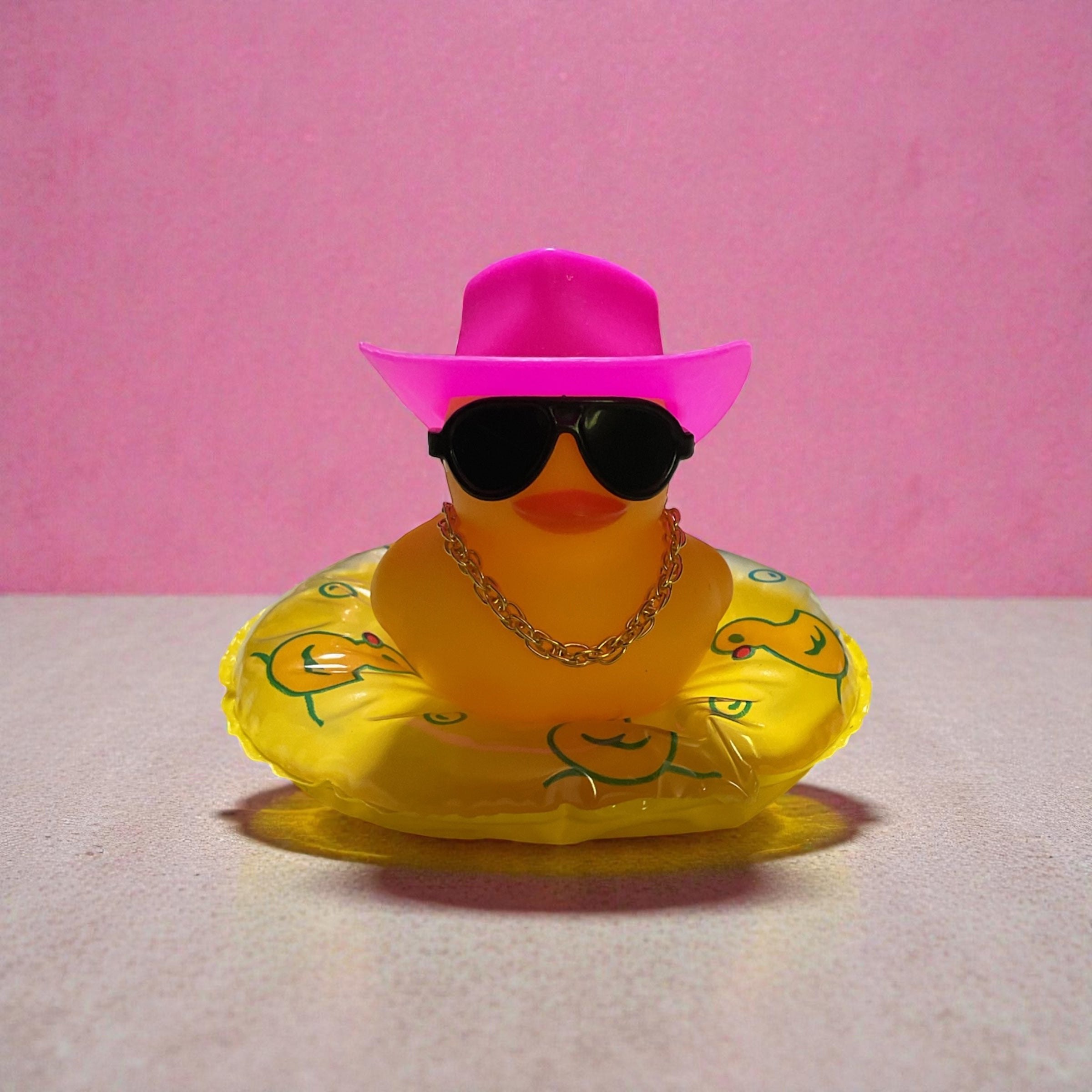 Yellow Duck with Pink Cowboy Hat, Black Sunglasses, Gold Necklace sitting on a Yellow Tube