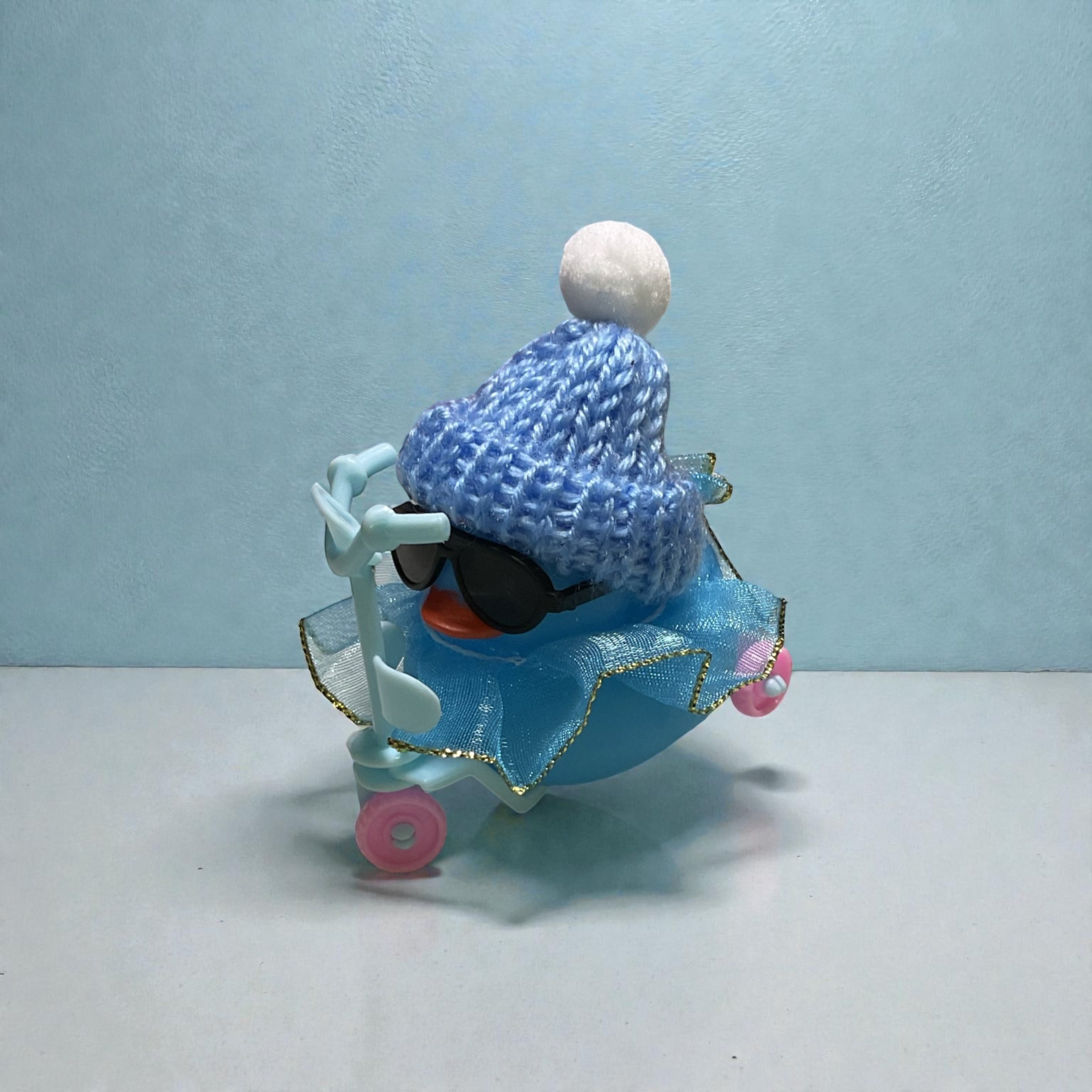 Blue Duck with Blue Stocking Cap and Dress, riding a scooter