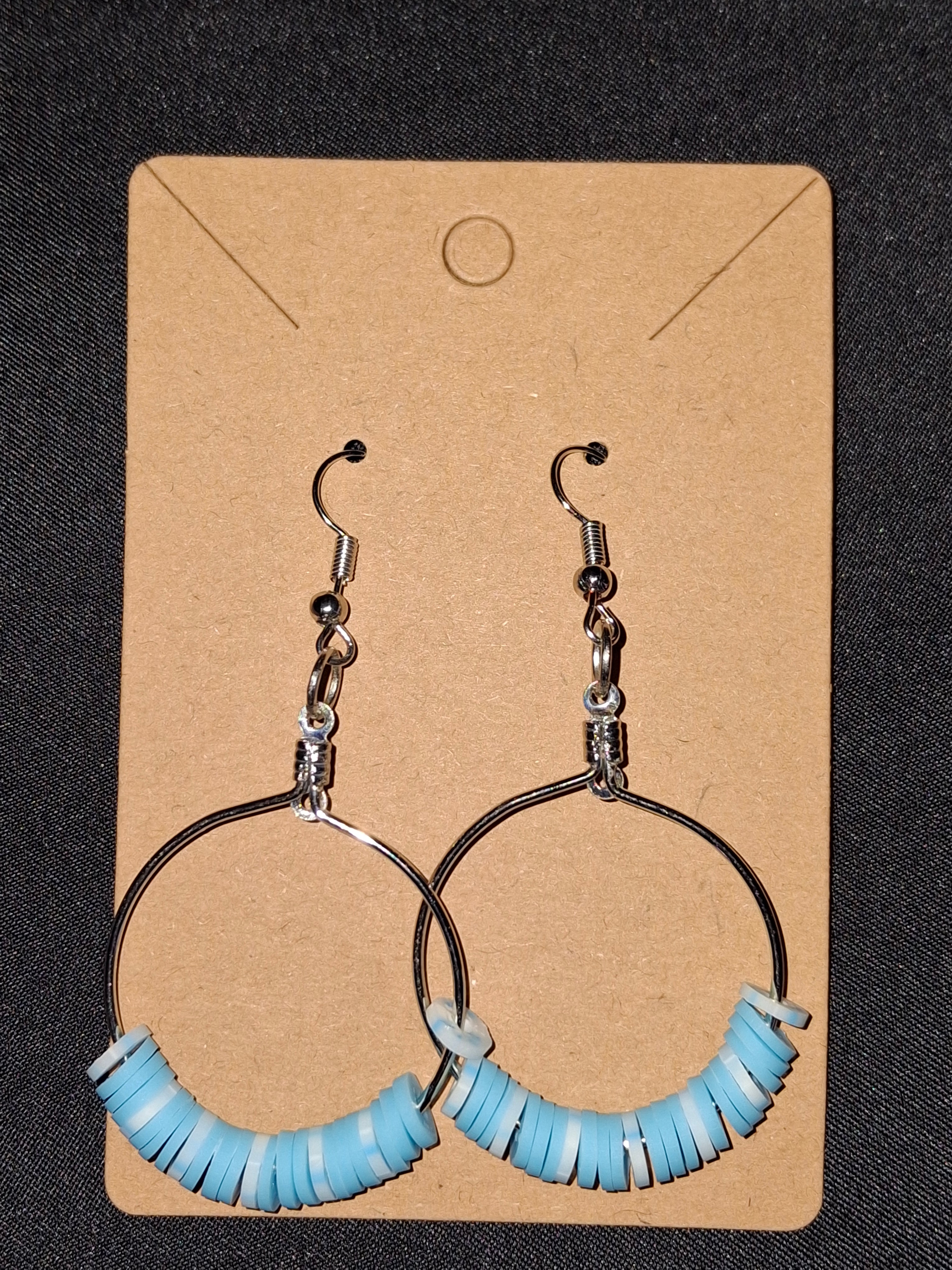 Pair of hoop earrings with blue and silver design on a cardboard backing.