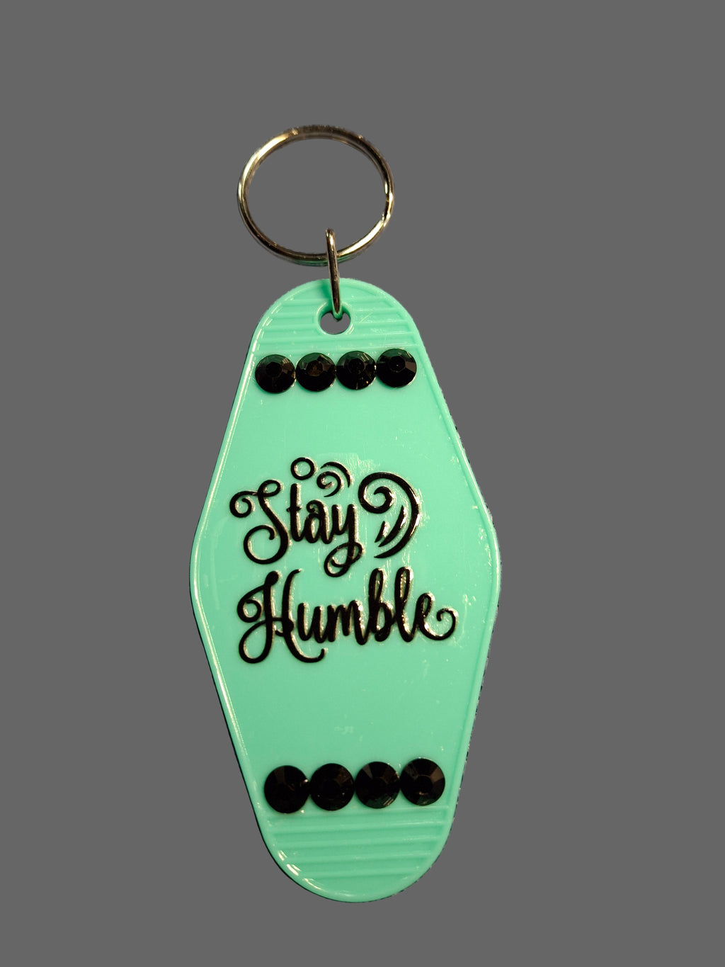 Green keychain with 'Stay Humble' text on a gray background