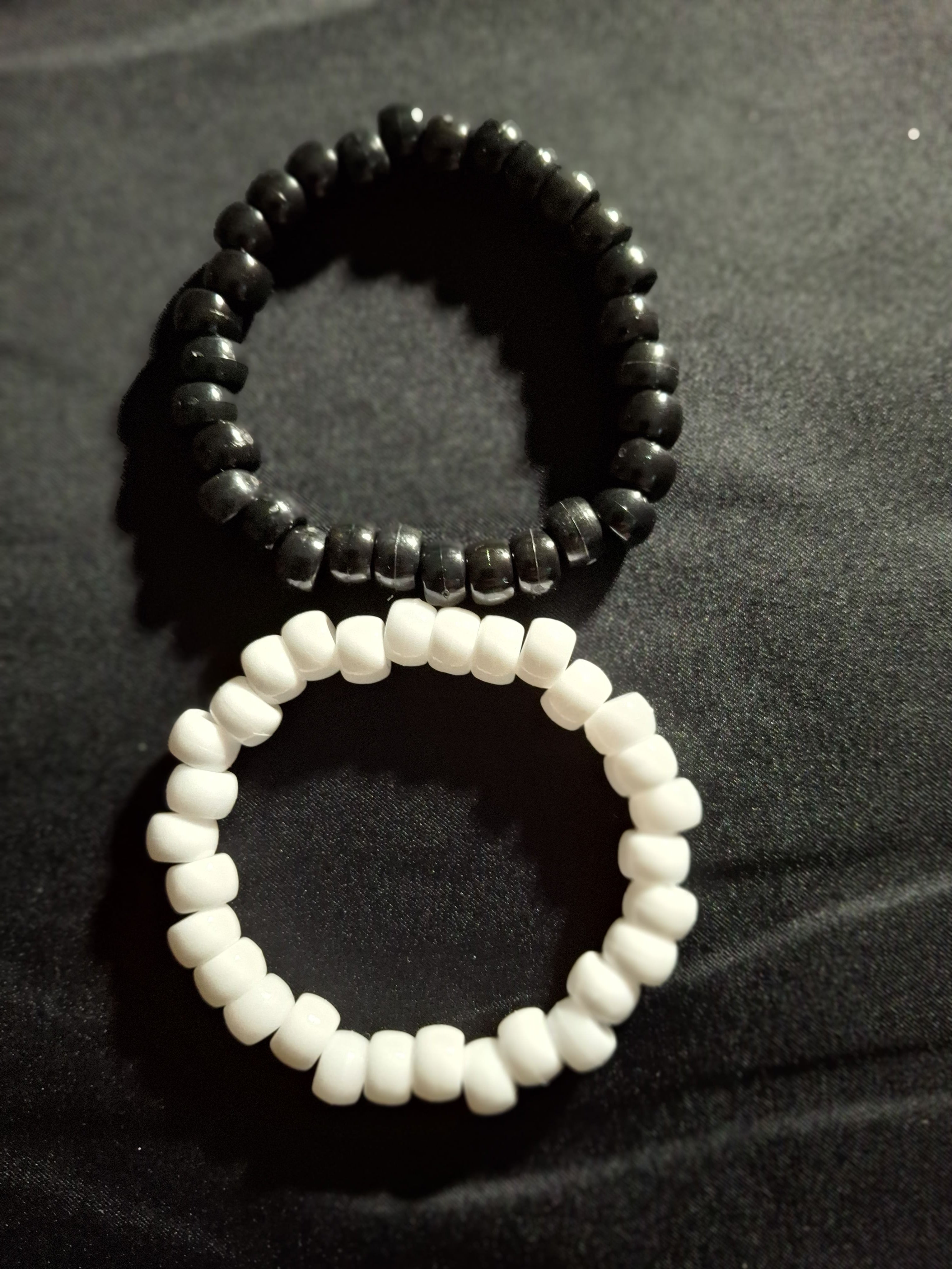 Black and white beaded bracelets on a dark fabric background
