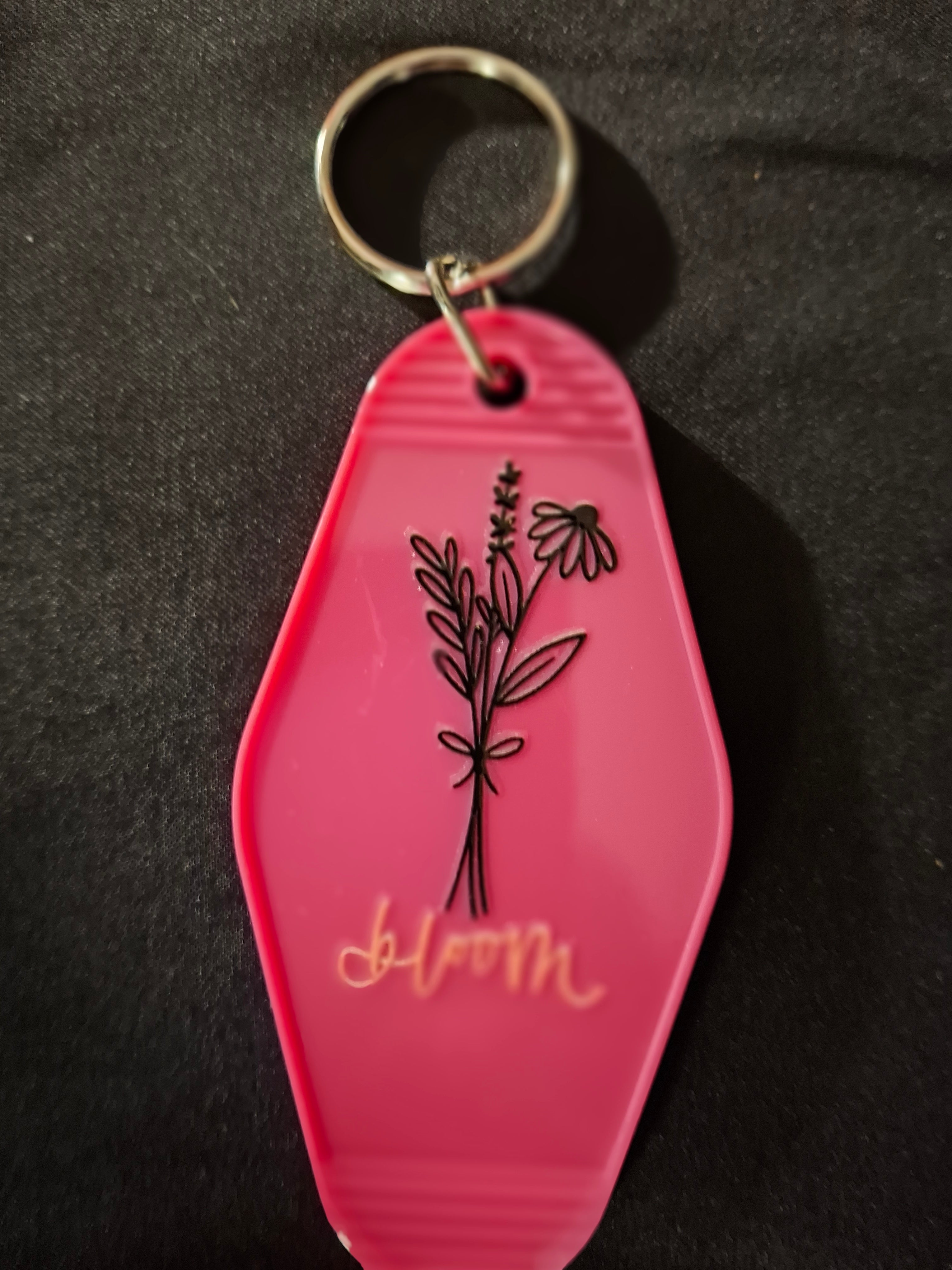 Pink keychain with floral design and 'Jubilee' text on a dark background