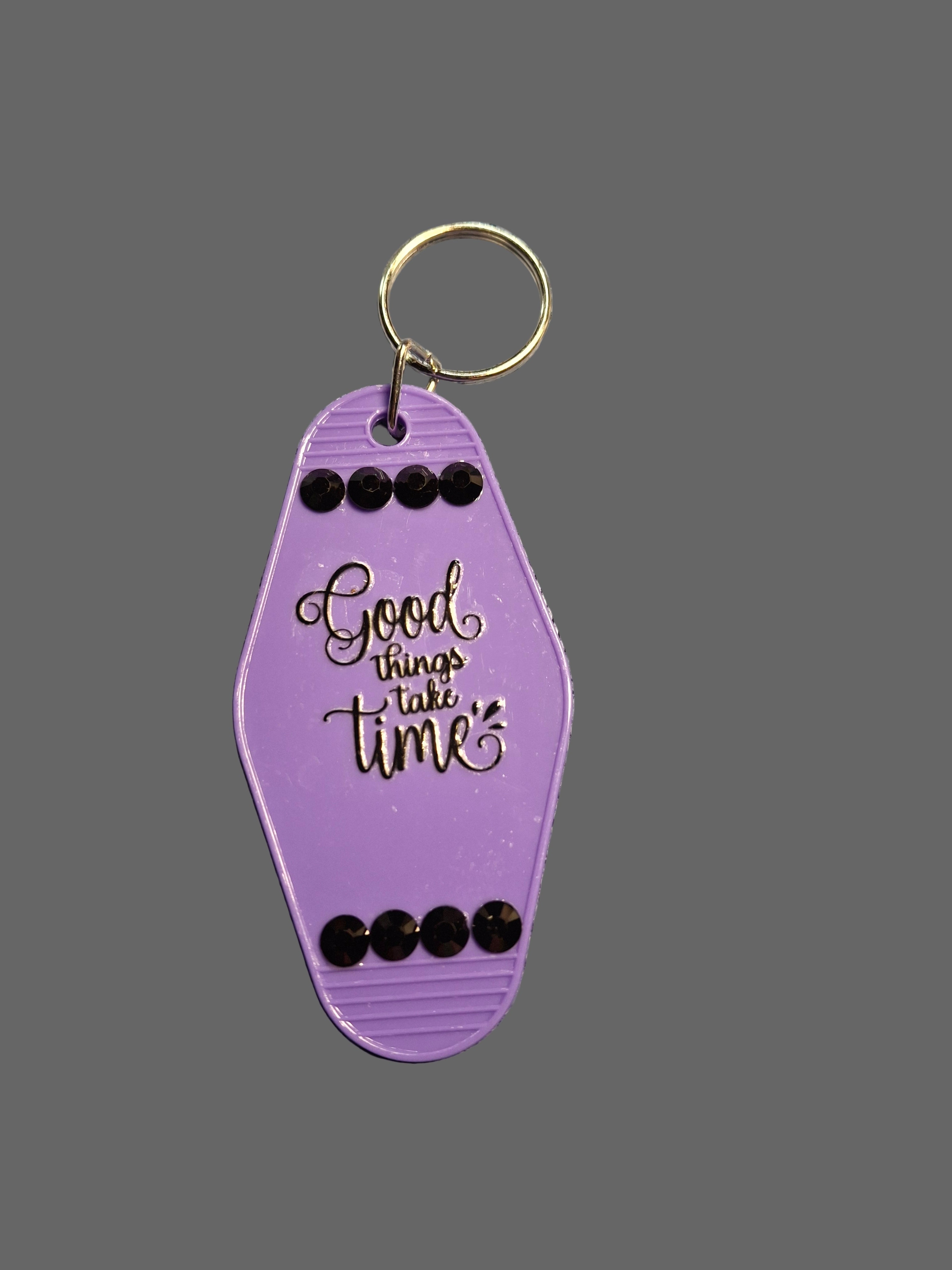 Purple keychain with 'Good things take time' text on a gray background