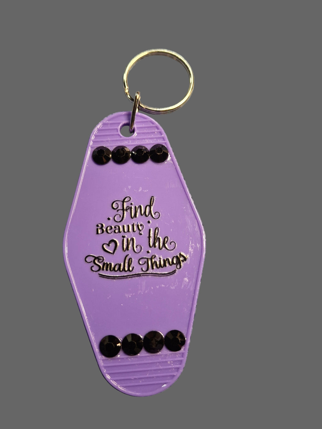 Purple keychain with decorative elements on a textured gray surface