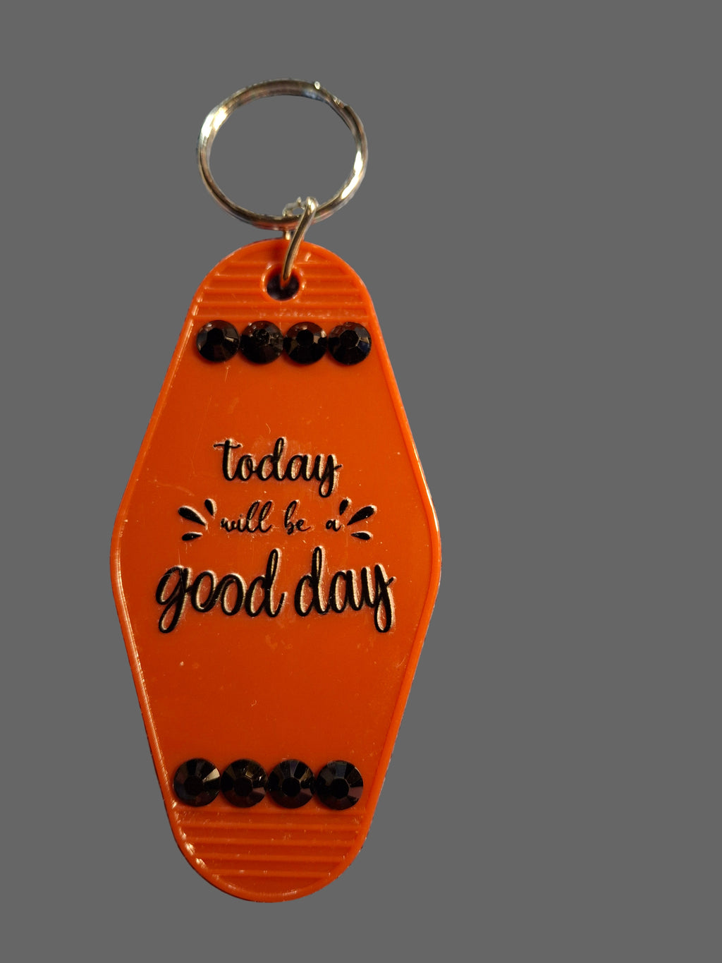Orange keychain with 'Today will be a good day' text on a textured gray background