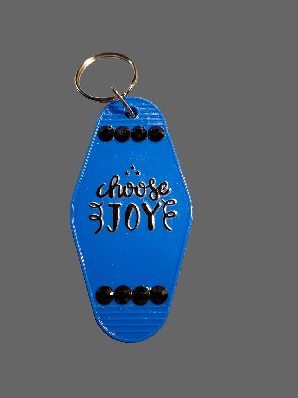 Blue keychain with 'Choose Joy' text on a textured gray background