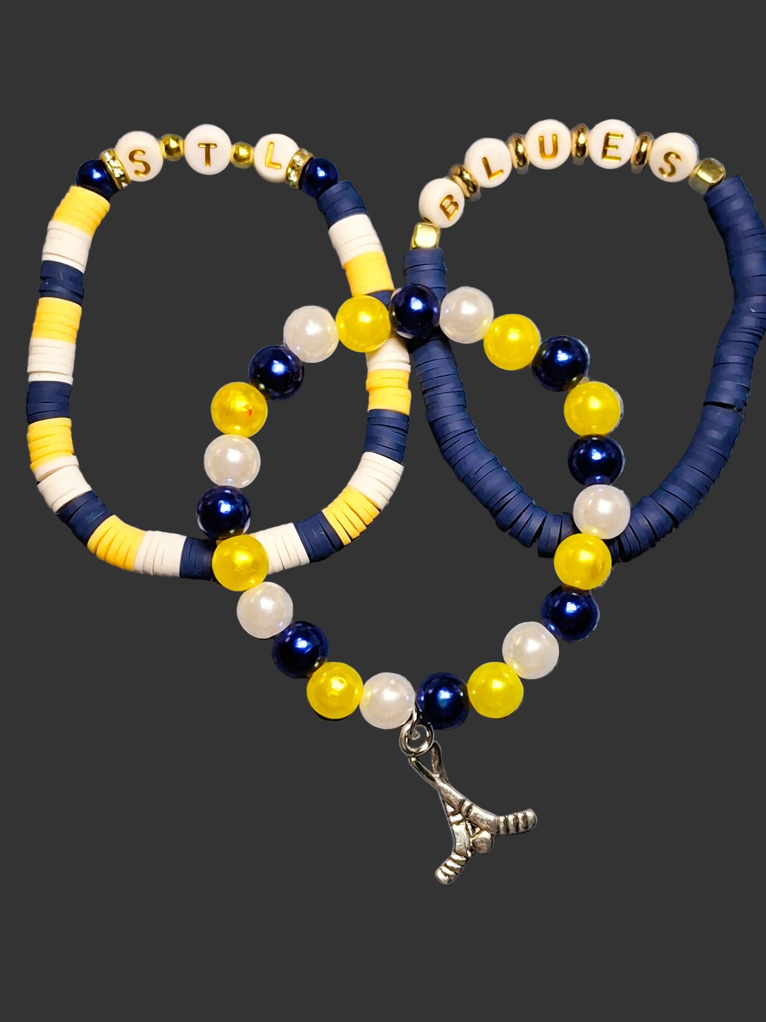 Two beaded bracelets with yellow, blue, and white beads on a textured blue background.