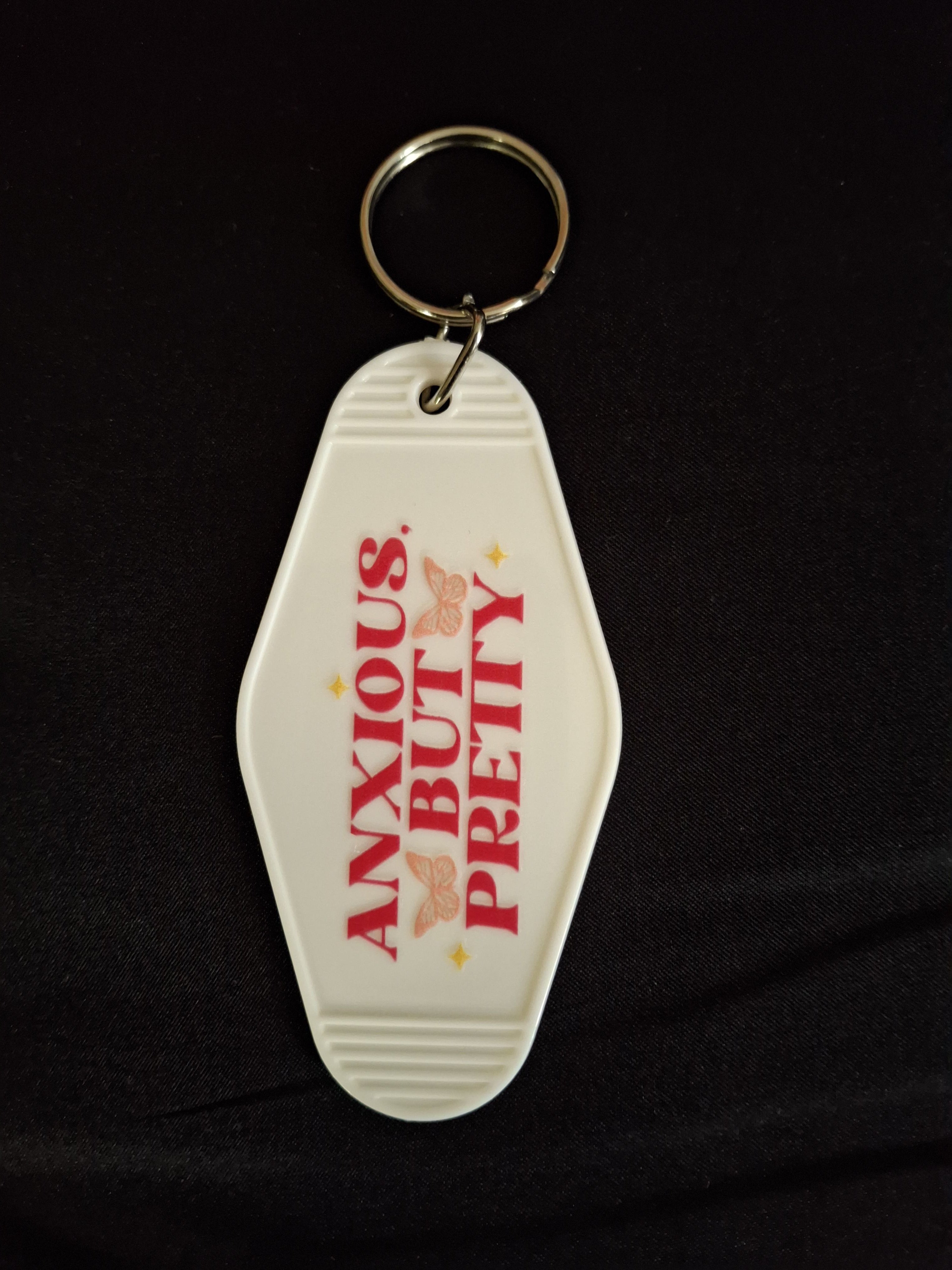 Keychain with text 'PRETTY BUT ANXIOUS' on a black background