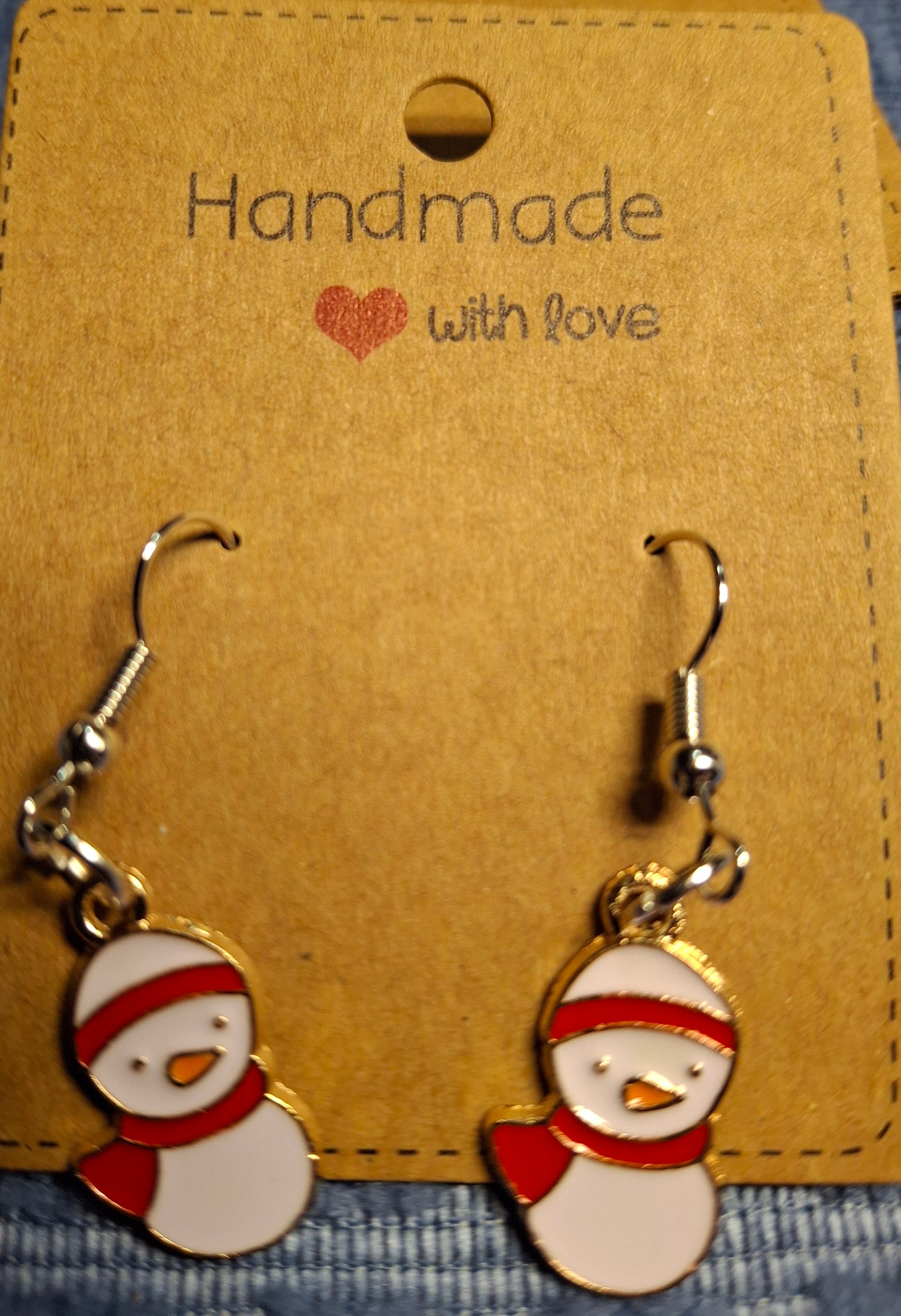 Snowman-shaped earrings on a 'Handmade with Love' card against a denim background